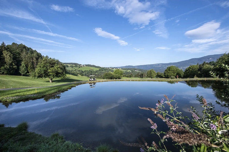 Wasserhinderniss Wasserhinderniss, im Hintergrund ein fahrendes Golfcaddy