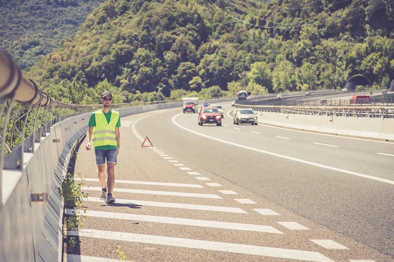 Warnweste bei einer Autopanne in Italien Panne auf einer italienischen Autobahn: Junger Mann in gelber Warneweste stellt Pannendreieck auf